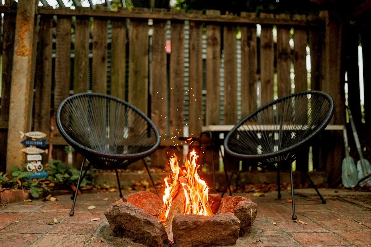 Tűzrakóhely a kertben, égő, megrakott tűzzel, székekkel